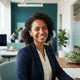 A friendly, diverse woman smiling confidently in a modern, well-lit professional environment.
