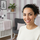 Headshot of a smiling, diverse mother in her late 20s to early 30s, looking confidently at the camera.